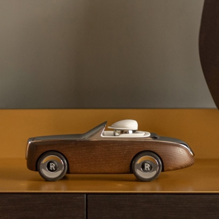 <p>Made from solid wood and polished aluminium, the Rolls-Royce Cameo has been designed to captivate and delight. This charming model comes complete with self-levelling Rolls-Royce centre caps and its very own driver.</p>
<p>Drawing inspiration from Rolls-Royce heritage, the Rolls-Royce Cameo distils the essence of our motor cars in their most elegant form. The construction of the model parallels the way we produce cars at the Home of Rolls-Royce, allowing its owner to assemble their own piece of Goodwood. The pieces assemble with a satisfying attraction and the marriage of wood, leather and aluminium create an authentic aesthetic. </p>
<p>The Rolls-Royce Cameo is a true collaboration of dedicated craftsmanship, design and engineering. </p>