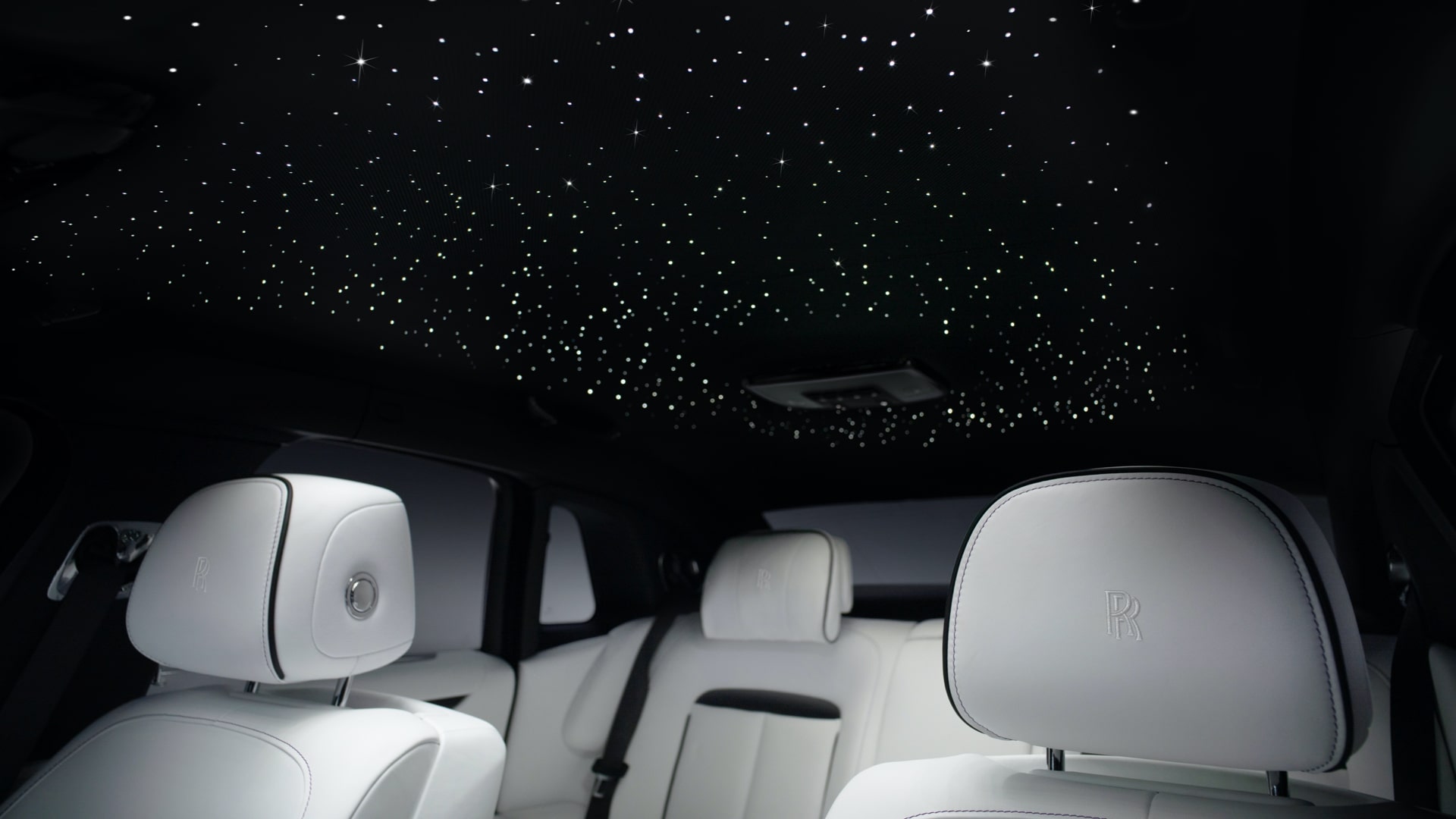 A shot of a star light headliner inside of a Rolls-Royce Ghost with white seats.