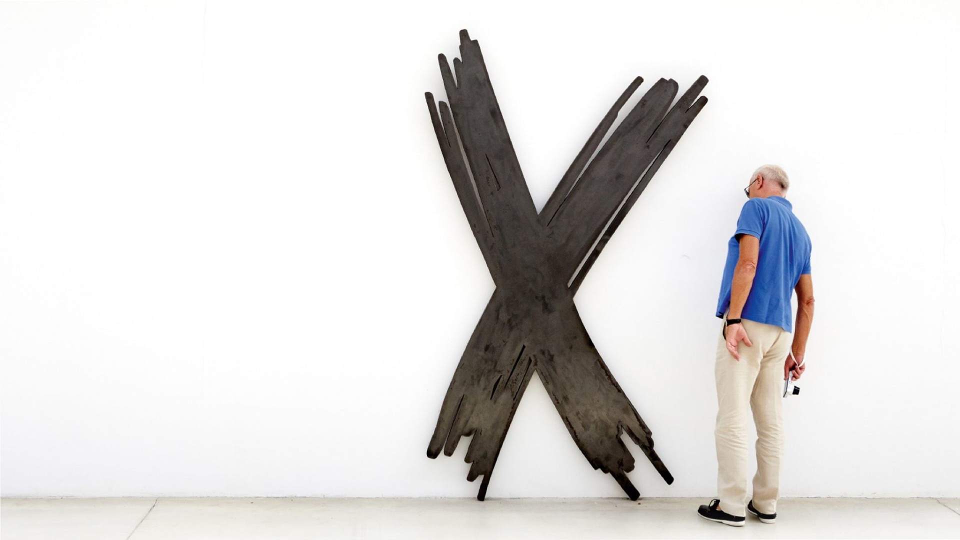 Bernar Venet standing in front of one of his contemporary sculptures