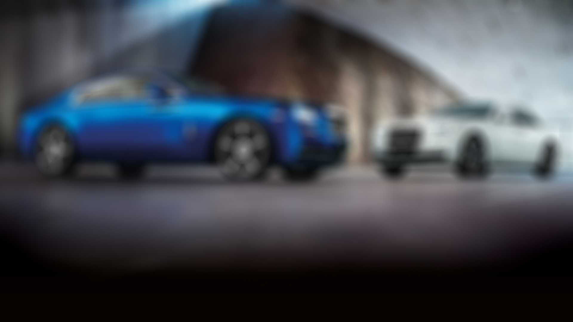 The exterior view of two Rolls-Royce's. On the left, a blue Rolls-Royce Wraith and on the right, a light grey Rolls-Royce Ghost