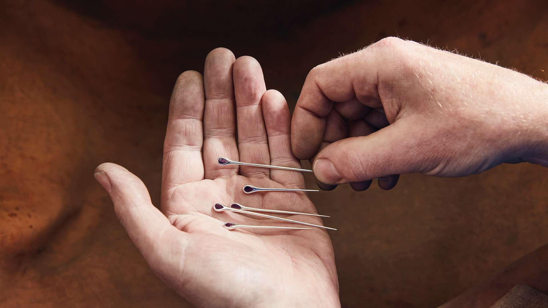 A craftsman holding some of the silver spokes set with amethyst that went into the Fox Silver Bespoke Phantom Gallery