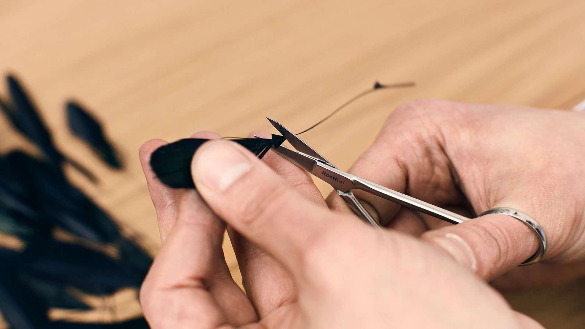 A close up of a craftsman working with one of the 3,000 iridescent tail feathers that made up a Bespoke Phantom Gallery