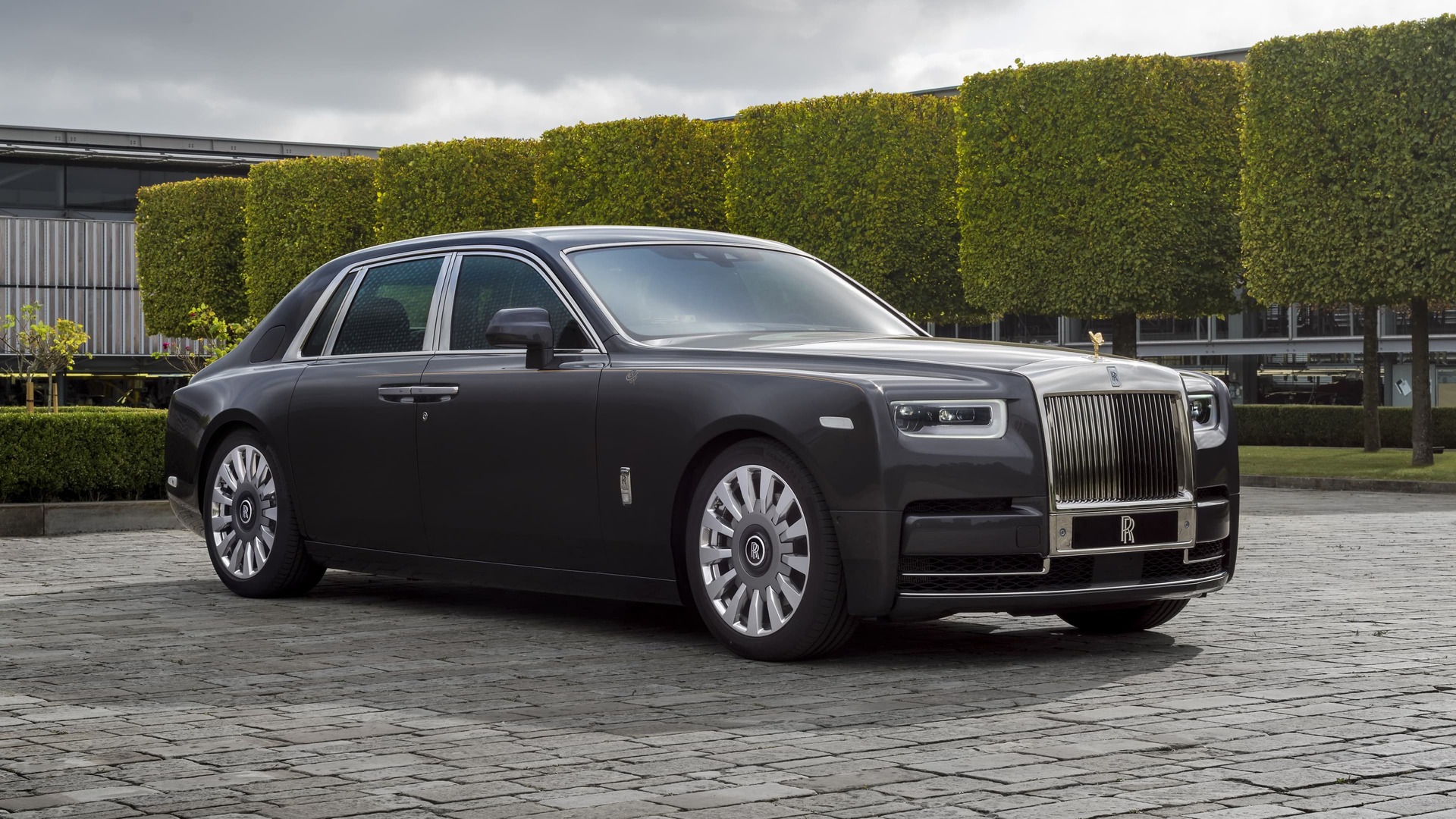 3/4 front view of the exterior of a stationary Rolls-Royce Horology Phantom motor car with greenery in background