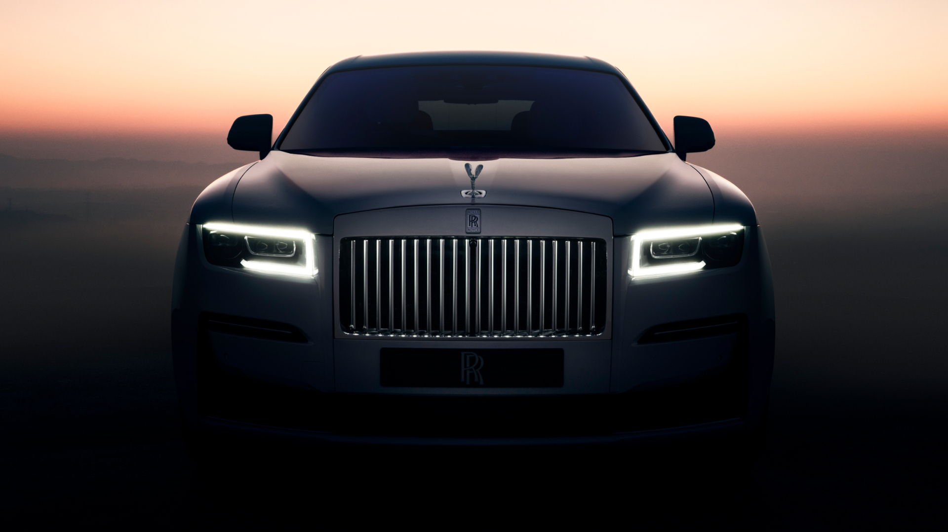Front on shot  of a Ghost with the illuminated grille on and sunset in the background 