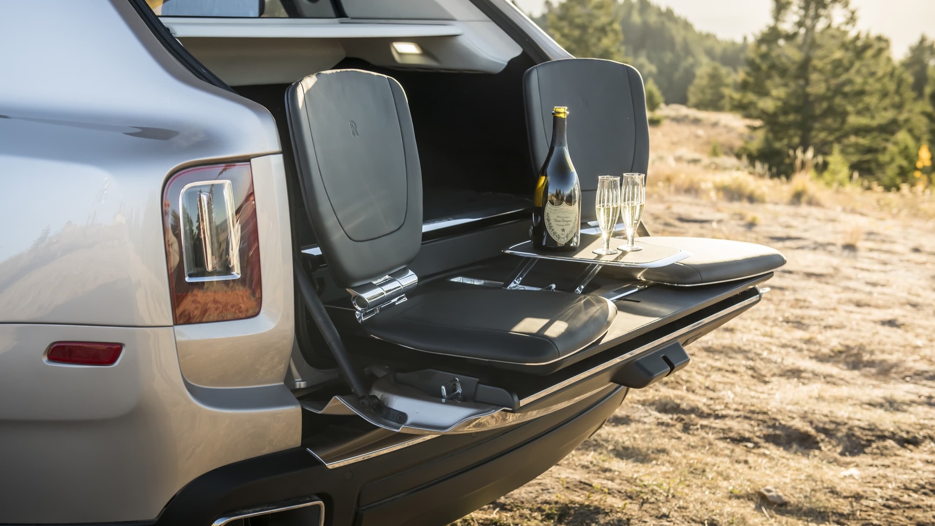 Rolls-Royce Cullinan motor car with rear door open and the bespoke Cullinan Viewing Suite set up with bottle of champagne