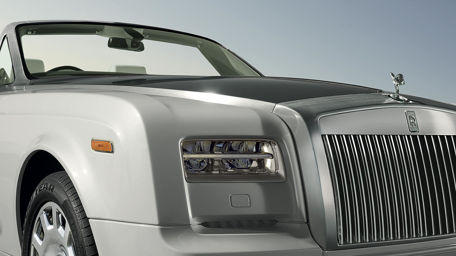 Close 3/4 front view of drop-head coupé Rolls-Royce motor car with roof down and bonnet and windscreen surrounds styled in brushed steel