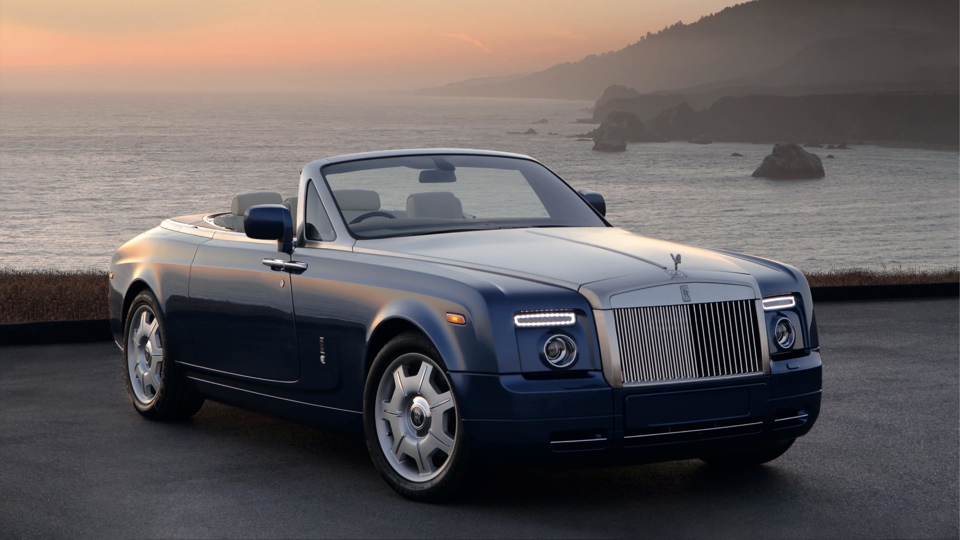  3/4 front view of drop-head coupé Rolls-Royce motor car with roof down and bonnet and windscreen surrounds styled in brushed steel