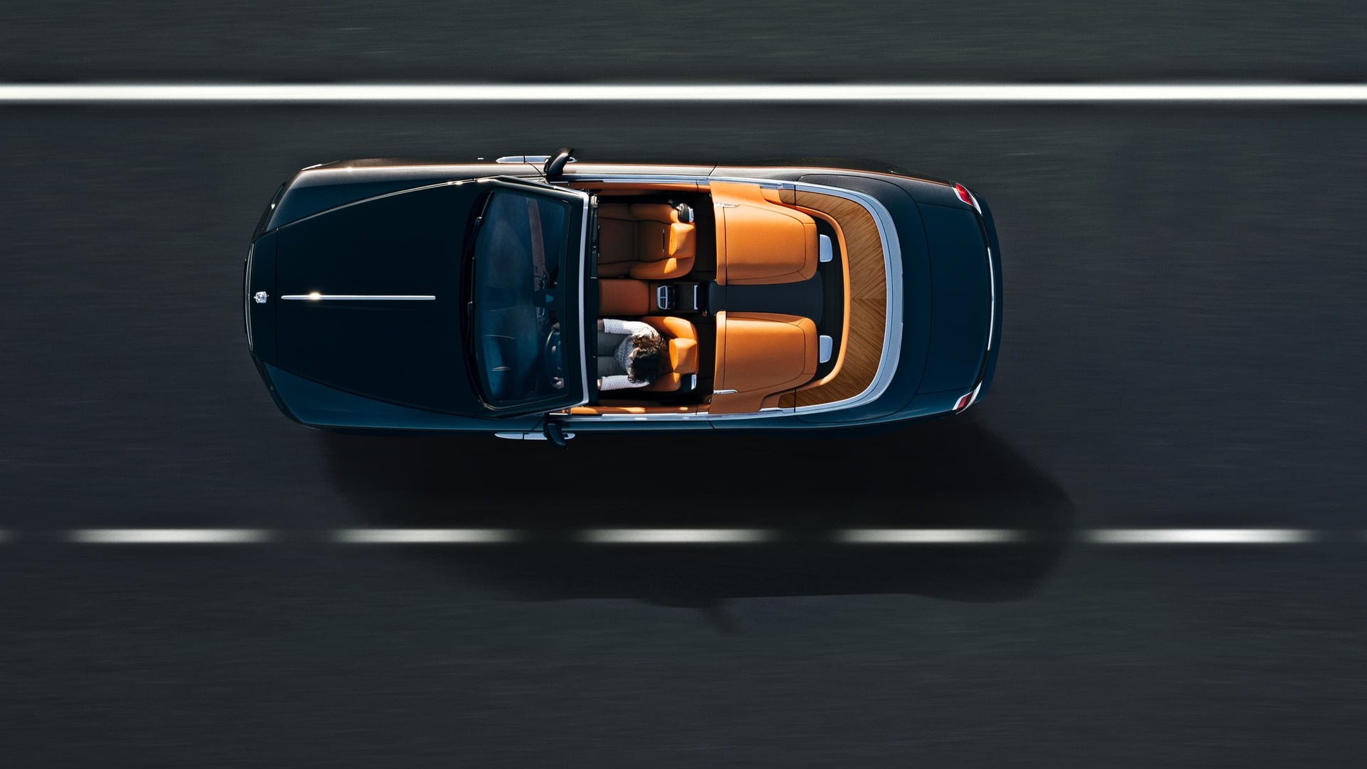 Aerial view of Rolls-Royce Dawn motor car with Dawn Aero Cowling Tonneau Cover roof open driving on road