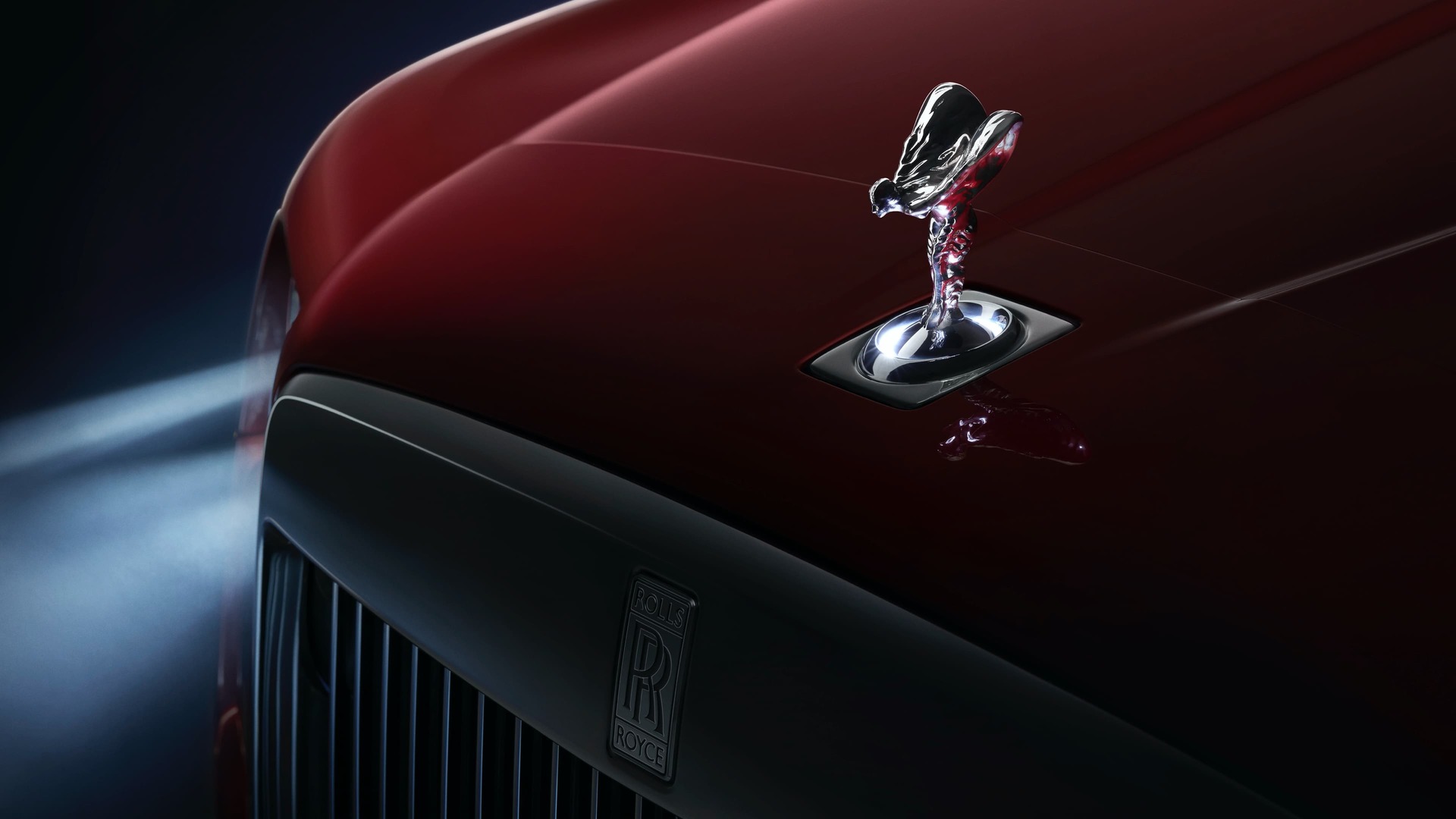 Front of a red Rolls-Royce Cullinan with an Uplit Spirit of Ecstasy.