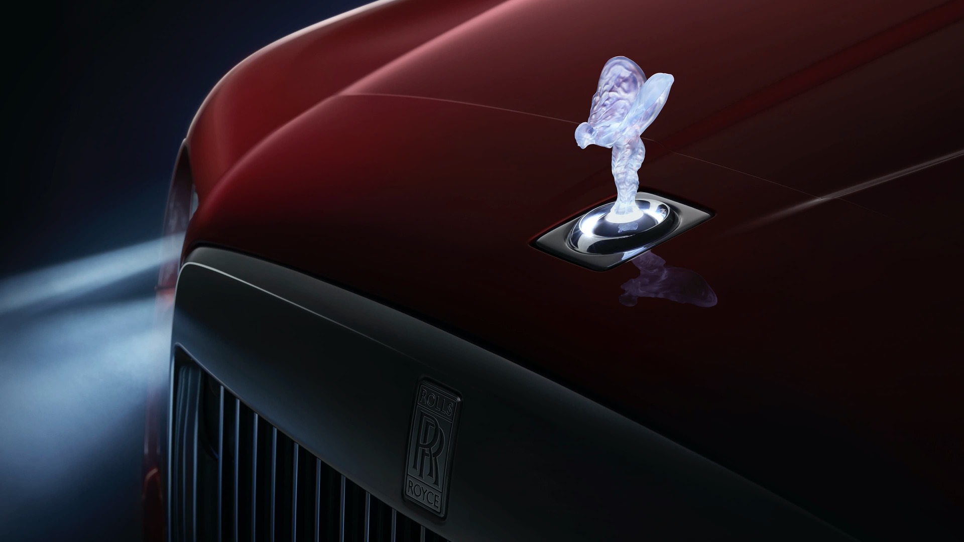 Front of a red Rolls-Royce Cullinan with an Illuminated Spirit of Ecstasy.