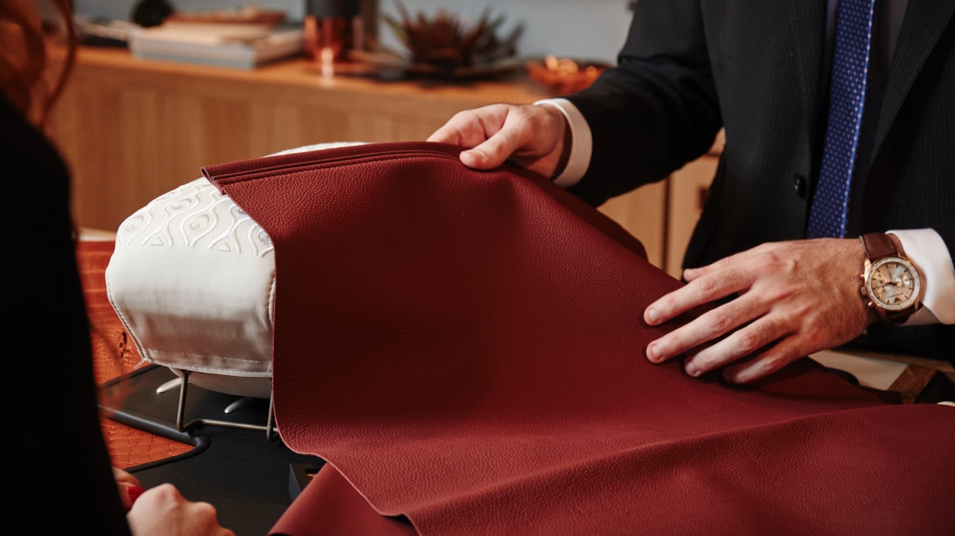 Consultant at Rolls-Royce certified dealer handles leather sample with client